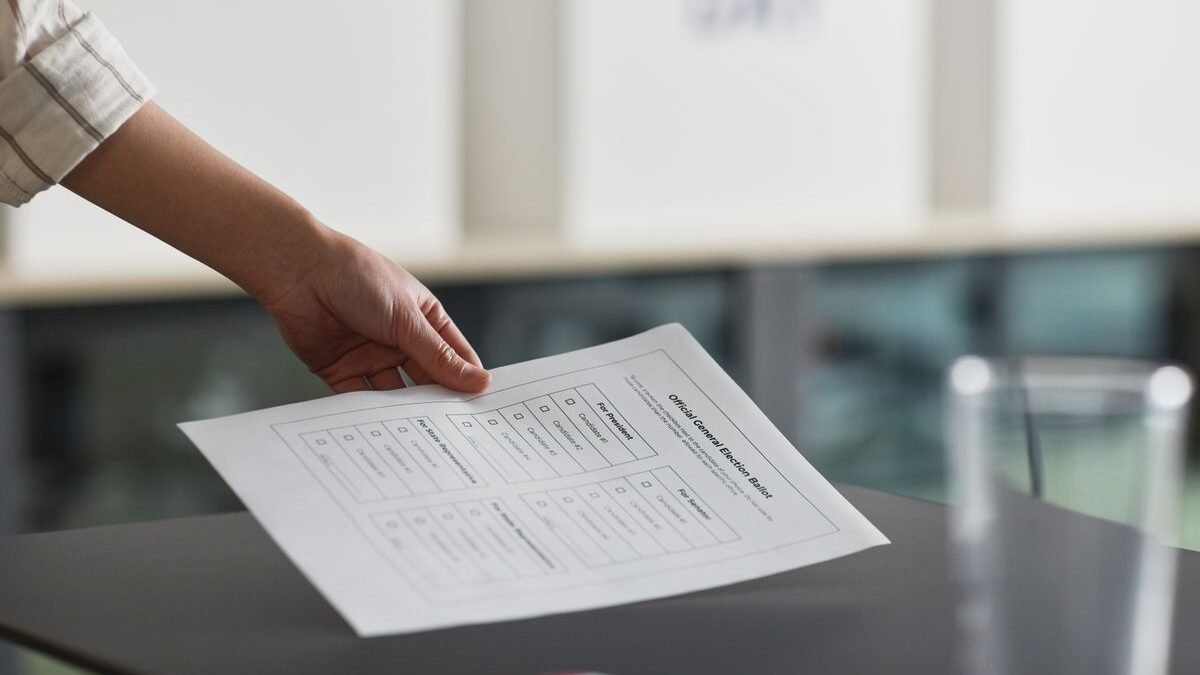 Close-up of a hand holding a ballot paper indoors