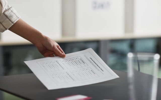 Close-up of a hand holding a ballot paper indoors