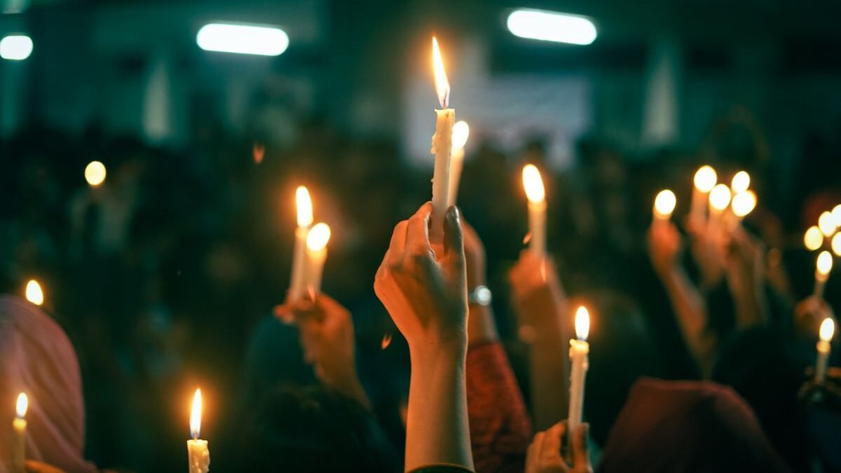 A crowd holds lit candles in a nighttime protest