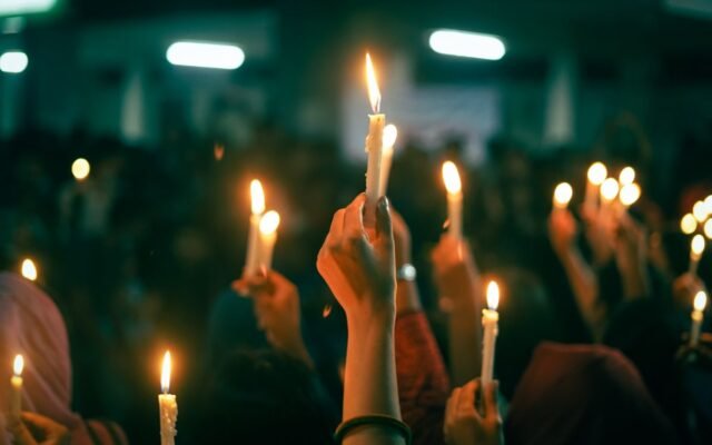 A crowd holds lit candles in a nighttime protest
