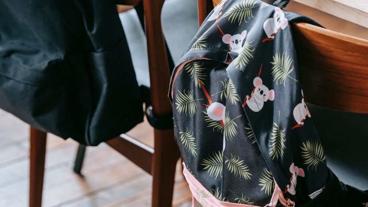 Wooden classroom setting with backpacks on chairs