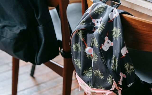 Wooden classroom setting with backpacks on chairs