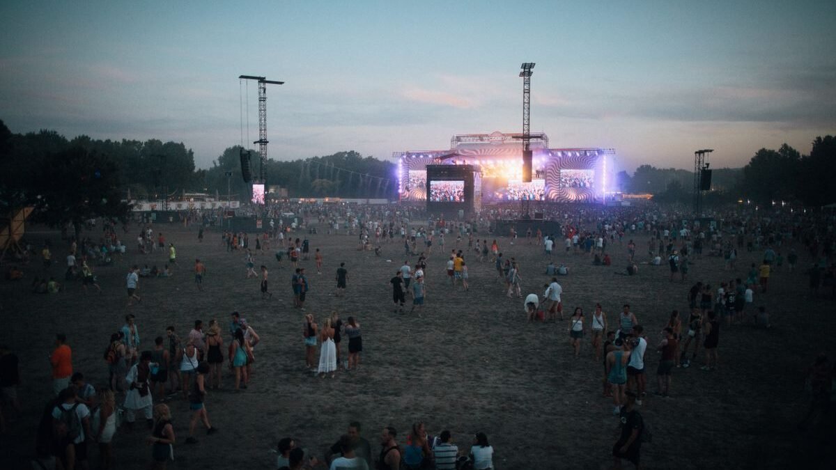 Vibrant outdoor concert scene with a lively crowd during dusk