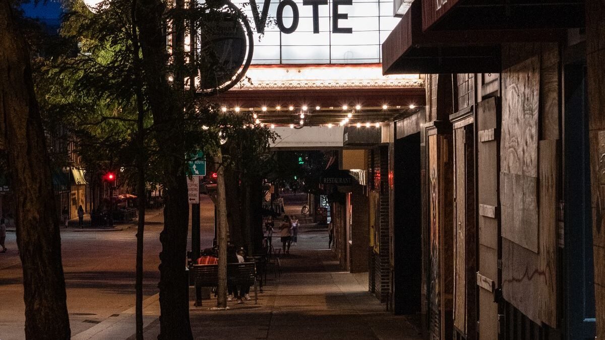 Nighttime city street scene with illuminated 'Vote' marquee sign