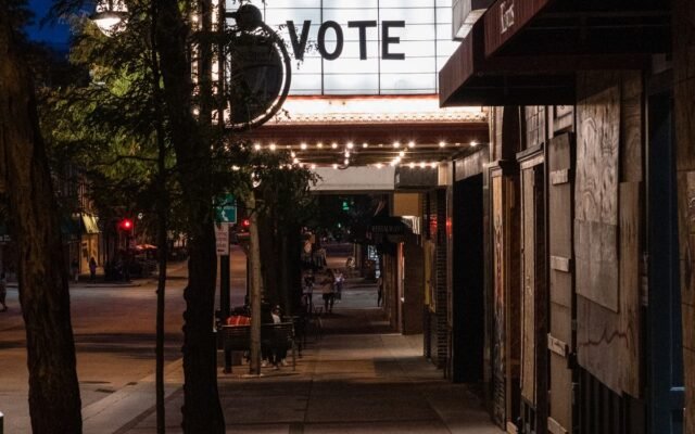 Nighttime city street scene with illuminated 'Vote' marquee sign