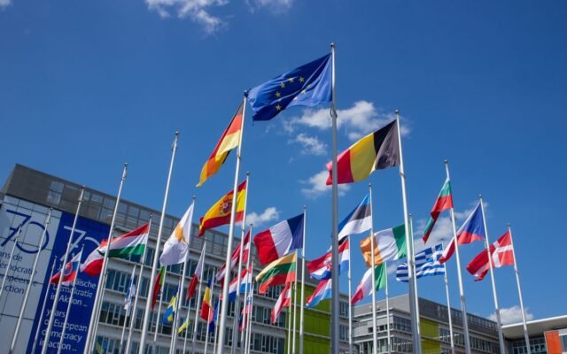 angle view of European Union flags on flagpoles against a blue sky