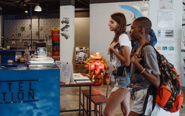 Two women with backpacks checking into a trendy hostel reception area