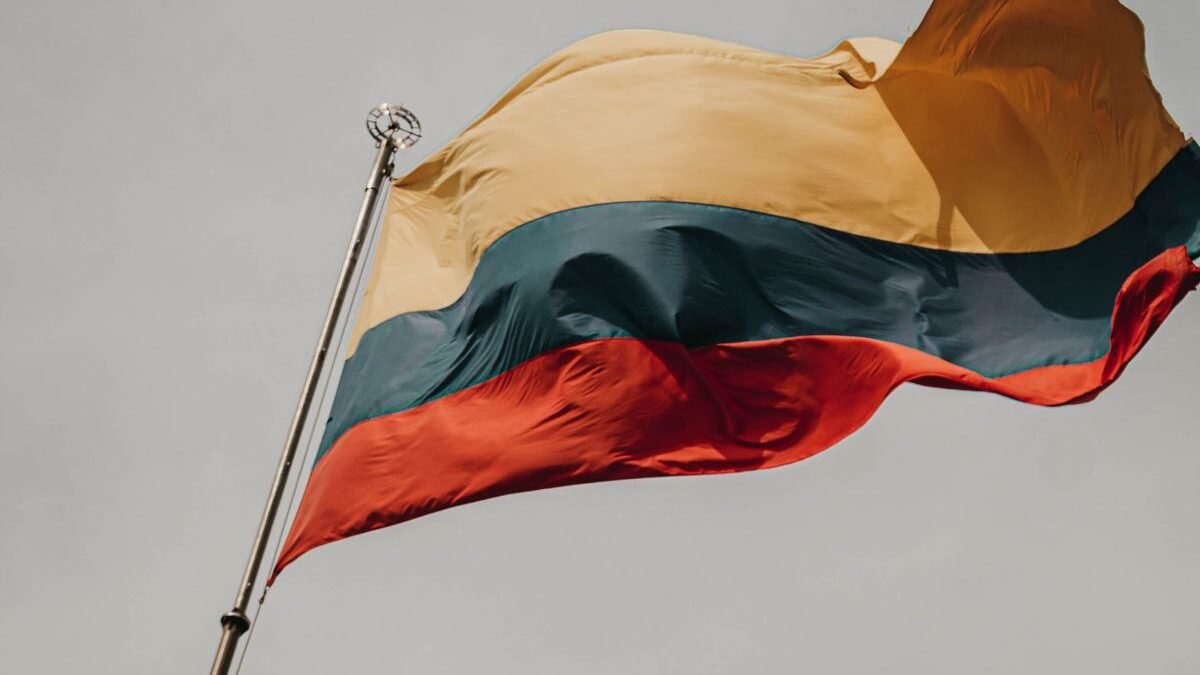 Close-up of the Lithuanian flag waving on a flagpole against a cloudy sky