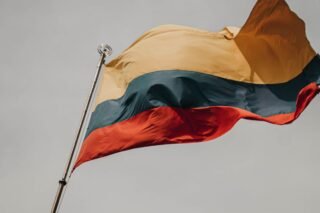 Close-up of the Lithuanian flag waving on a flagpole against a cloudy sky