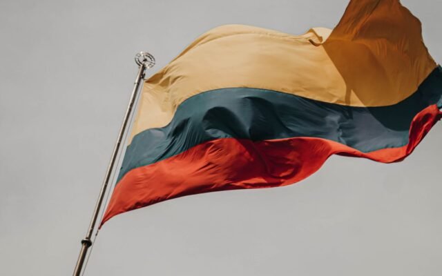 Close-up of the Lithuanian flag waving on a flagpole against a cloudy sky