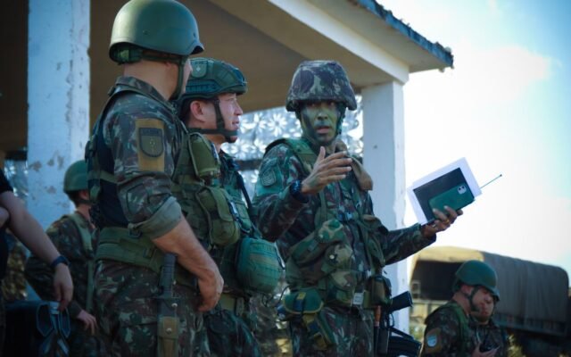 Group of soldiers in camouflage attending a briefing outdoors with tactical gear and helmets