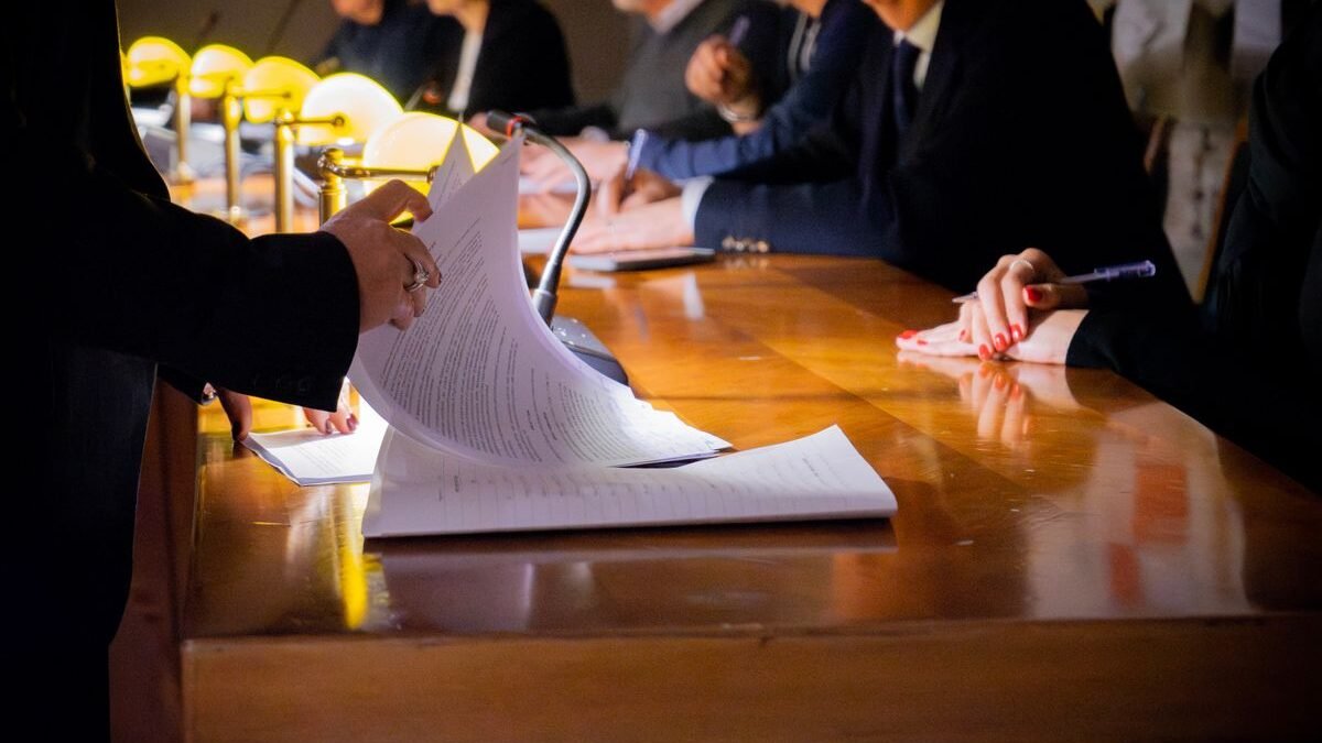 Close-up of a business meeting table with documents being reviewed and signed