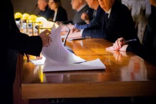 Close-up of a business meeting table with documents being reviewed and signed
