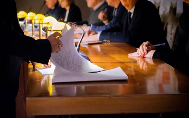 Close-up of a business meeting table with documents being reviewed and signed