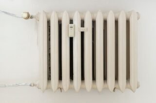 A classic white metal radiator on a plain wall