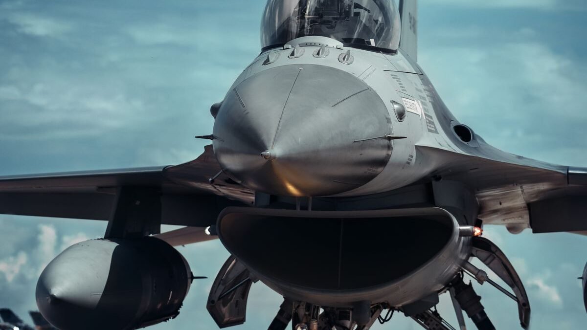 Front view of a fighter jet on a runway under a bright blue sky