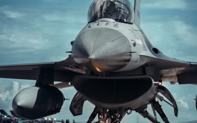 Front view of a fighter jet on a runway under a bright blue sky