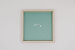 Minimalist wooden frame with 'Vote' text on green backdrop