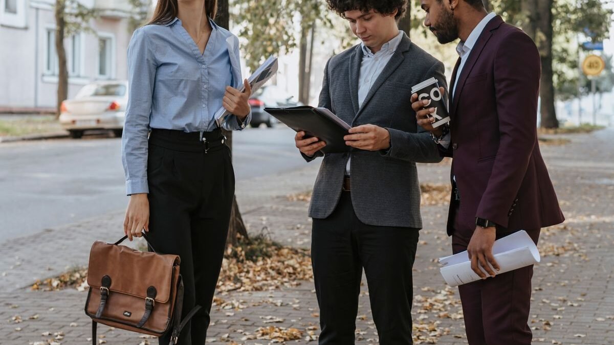Group of diverse young professionals discussing work outdoors on a tree-lined sidewalk