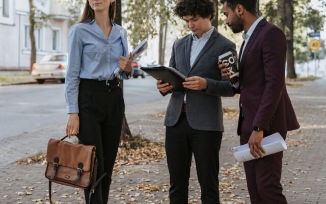 Group of diverse young professionals discussing work outdoors on a tree-lined sidewalk